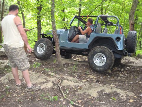 2005 Jeep Wrangler - A blue Jeep Wrangler navigates a challenging rocky terrain on an off-road trail.