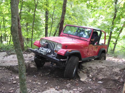 2005 Jeep Wrangler - Red Jeep Wrangler tackling a challenging rocky trail with a winch installed.