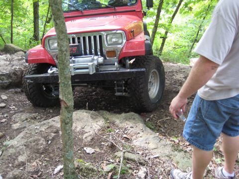 2005 Jeep Wrangler - This Jeep Wrangler is navigating a challenging off-road course with large rocks and trees.