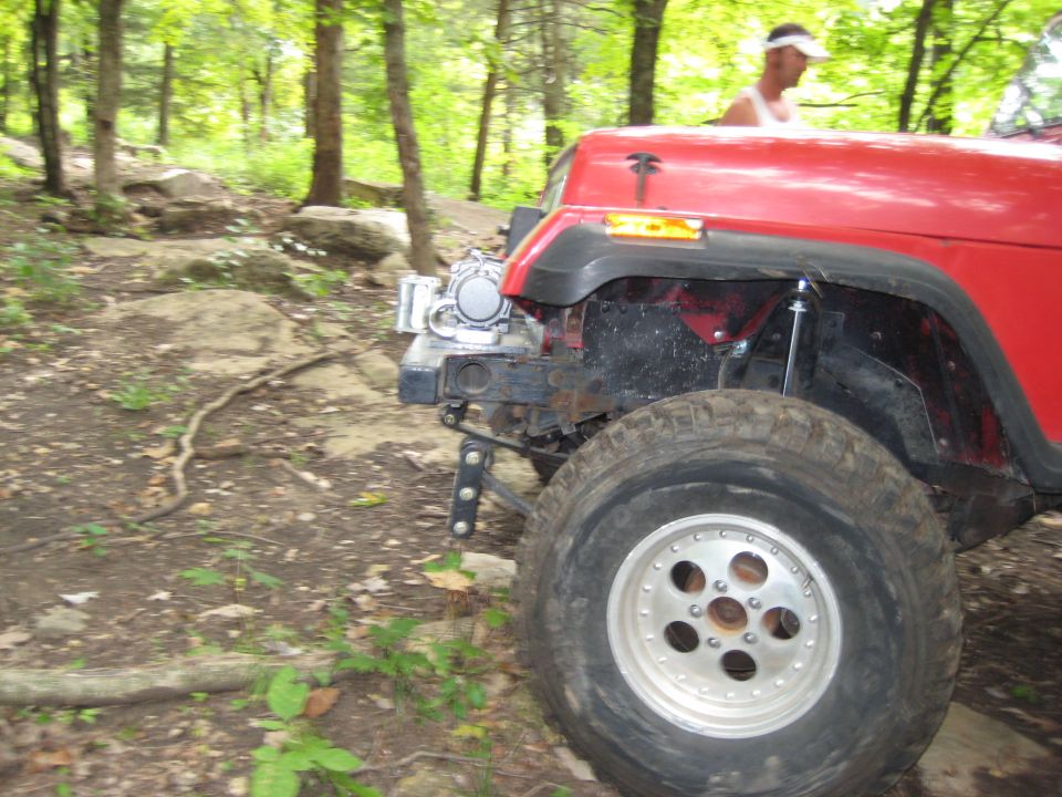 Red Jeep Wrangler front fender and wheel on rocky terrain