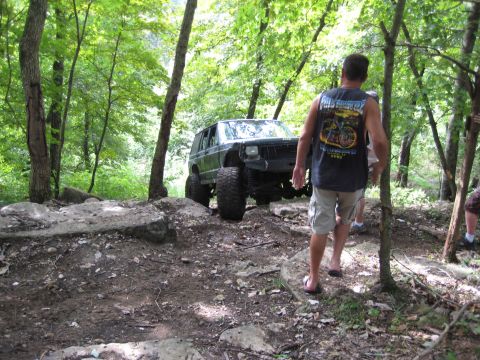 2005 Jeep Wrangler - A modified Jeep navigates a rocky trail through a dense forest.