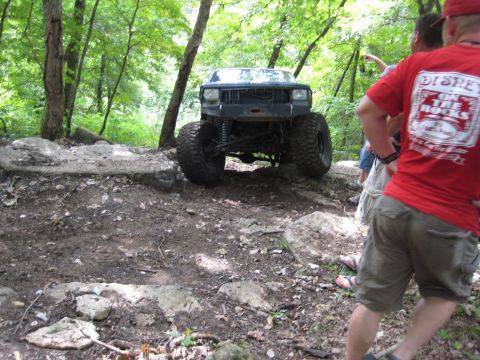 2005 Jeep Wrangler - A modified Jeep Cherokee XJ navigates a challenging off-road course with spectators present.