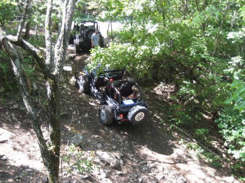 2005 Jeep Wrangler - Two Jeep Wranglers tackle a challenging off-road trail in a wooded area.