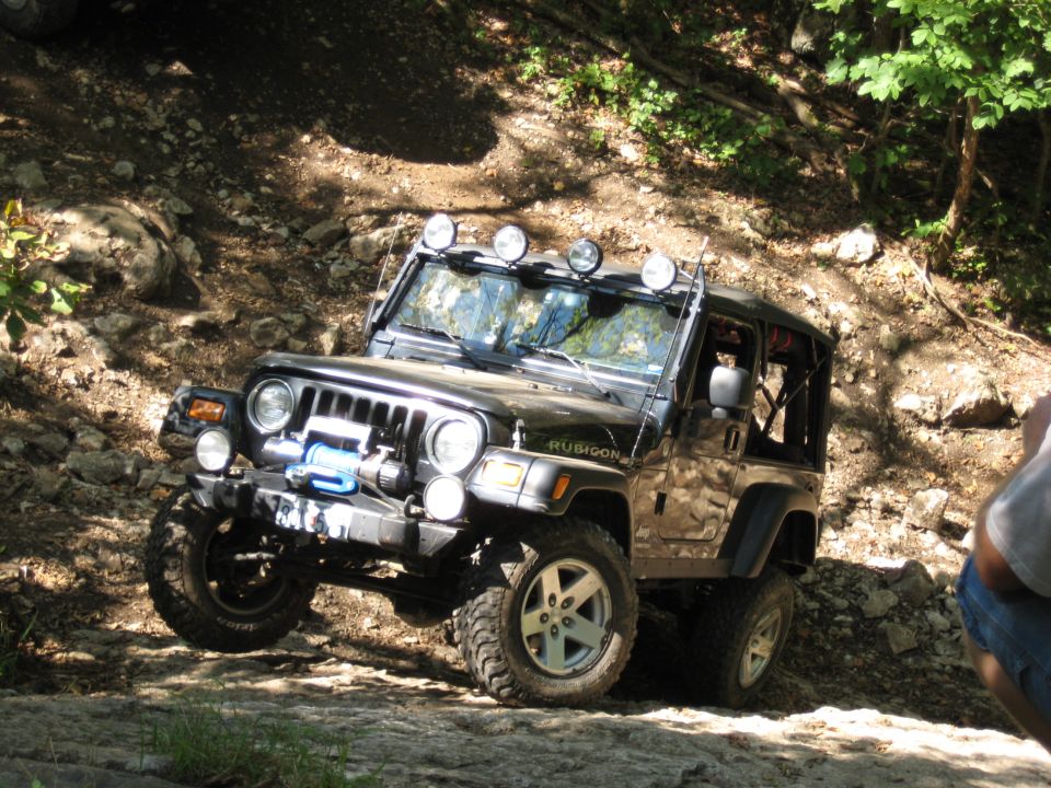 Black Jeep Wrangler Rubicon with winch and light bar on rocky terrain