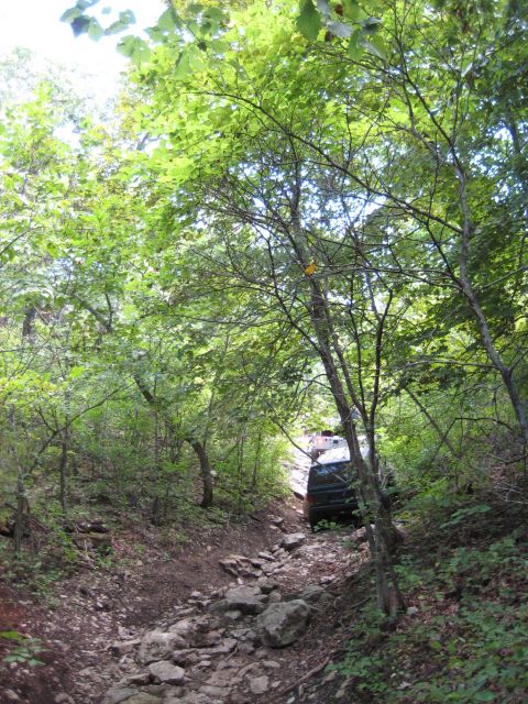 2005 Jeep Wrangler - A Jeep Wrangler navigates a challenging, rocky path through a dense forest.
