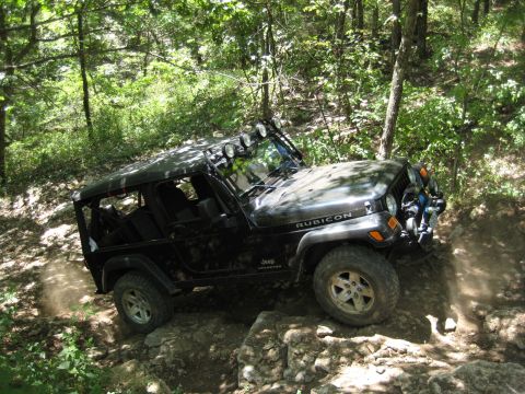 2005 Jeep Wrangler - 2005 Jeep Wrangler Rubicon navigating a challenging rocky path in a wooded area.