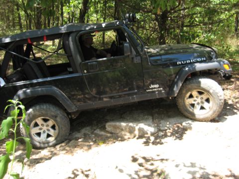 2005 Jeep Wrangler - A black Jeep Wrangler Rubicon Unlimited navigates a rocky trail with a driver inside.