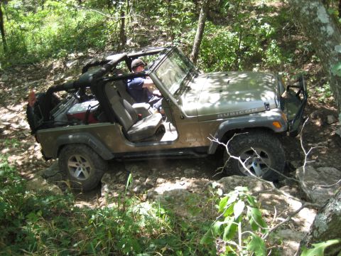 2005 Jeep Wrangler - A 2005 Jeep Wrangler Rubicon navigates a challenging rocky terrain on a wooded trail.