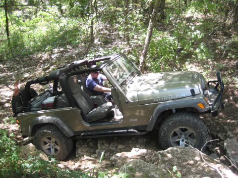 2005 Jeep Wrangler - A 2005 Jeep Wrangler Rubicon navigates a challenging rocky path through a wooded area.