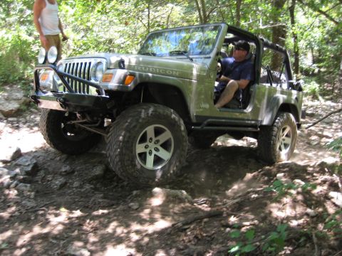 2005 Jeep Wrangler - A Jeep Wrangler Rubicon navigates a challenging off-road path, kicking up dirt as it goes.