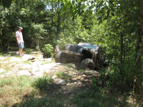 2005 Jeep Wrangler - A Jeep Wrangler navigates a challenging off-road course through a wooded area.