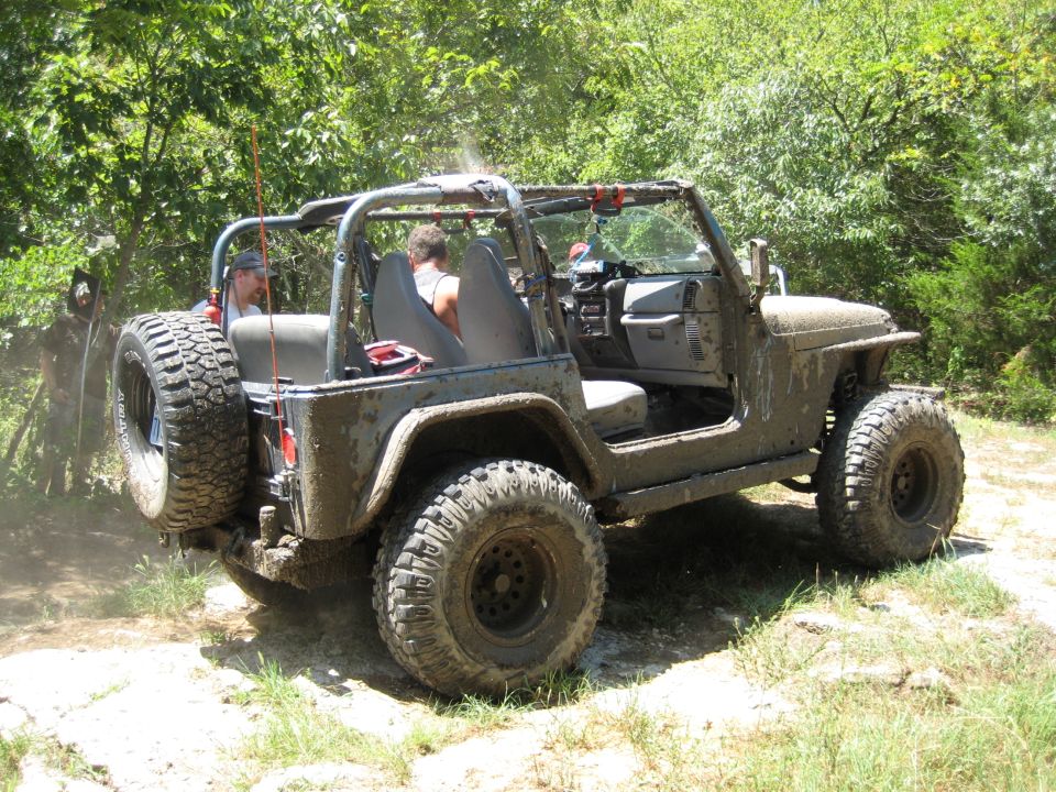 Mud-covered 2005 Jeep Wrangler driving off-road