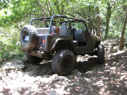 2005 Jeep Wrangler - A 2005 Jeep Wrangler navigates a challenging rocky path through a wooded area.