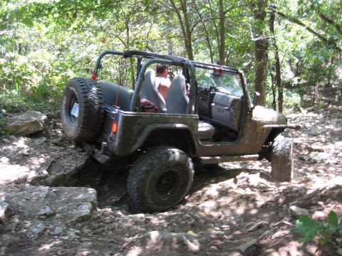 2005 Jeep Wrangler - A 2005 Jeep Wrangler tackles a challenging, rocky path through a wooded area.