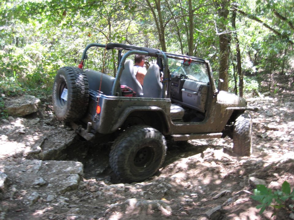 Dark green 2005 Jeep Wrangler navigating a rocky off-road trail