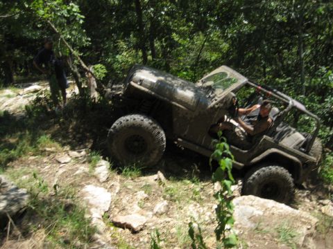2005 Jeep Wrangler - A Jeep Wrangler navigates a challenging off-road trail covered in mud and rocks.