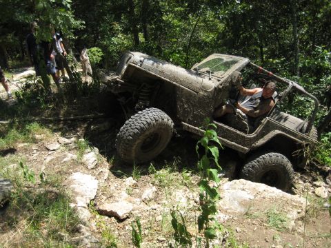 2005 Jeep Wrangler - A Jeep navigates a challenging off-road course, covered in mud and dirt.