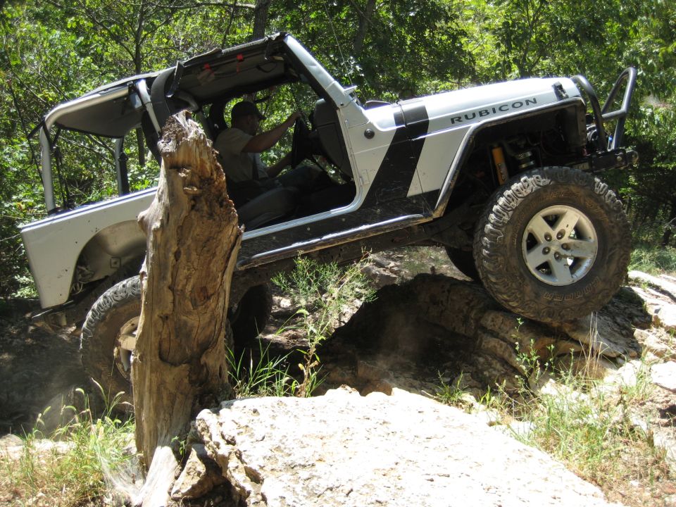 2005 Jeep Wrangler Rubicon climbing over a large log on a rocky trail