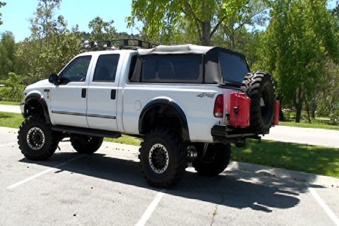 2000 Ford F-250 - This white Ford F-250 Super Duty pickup truck is modified with large tires and a soft tonneau cover.