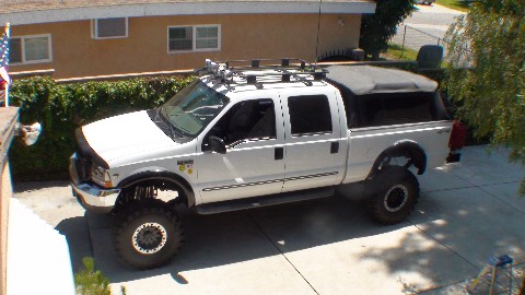 2000 Ford F-250 - This 2000 Ford F-250 Super Duty pickup truck is equipped with a cap and roof rack, seen from a 3q-front angle.