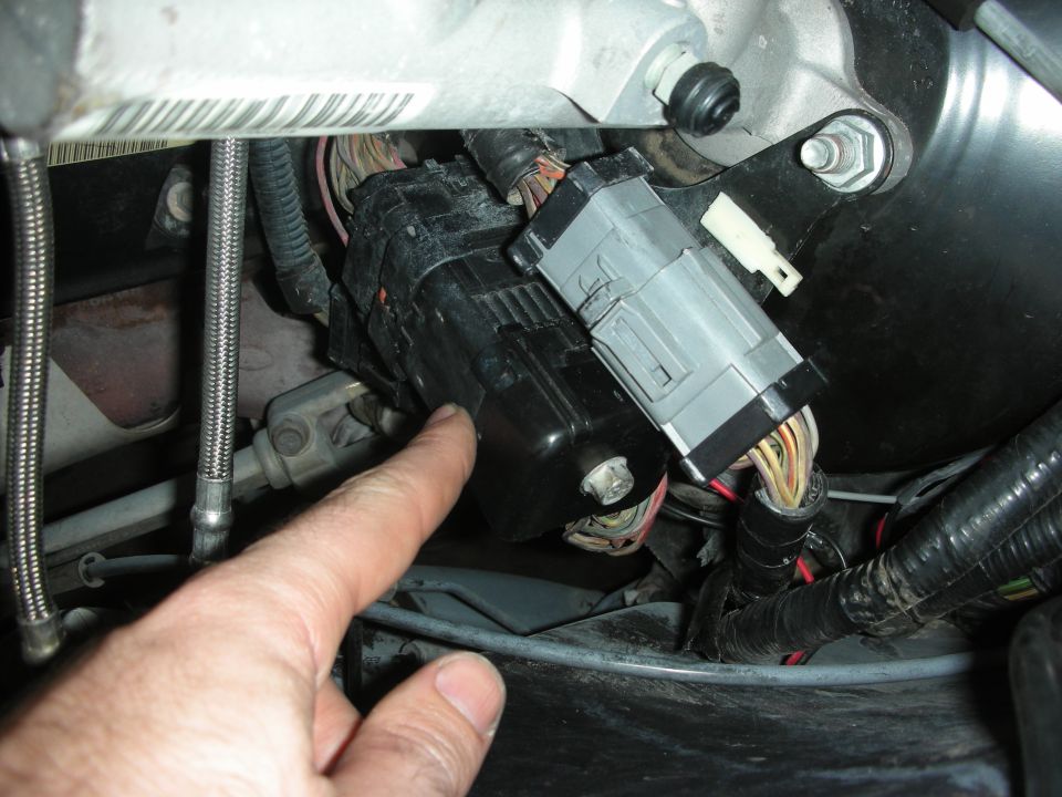 Finger pointing at a black electrical connector with gray housing and multiple wires