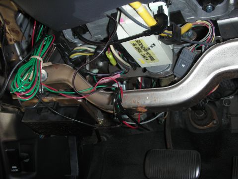 2004 Ford Crown Victoria - A close-up view of the complex wiring harness and electronic components located beneath the dashboard.