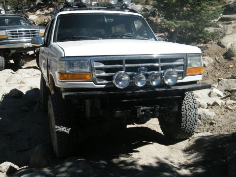 1982 Ford Bronco - White Ford Bronco on a rocky trail, with another vehicle in the background.