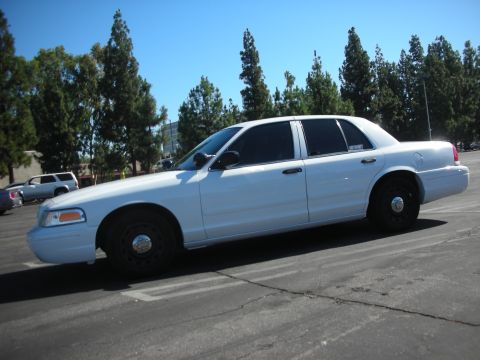 2004 Ford Crown Victoria - Side view of a white 2004 Ford Crown Victoria sedan parked in a lot.