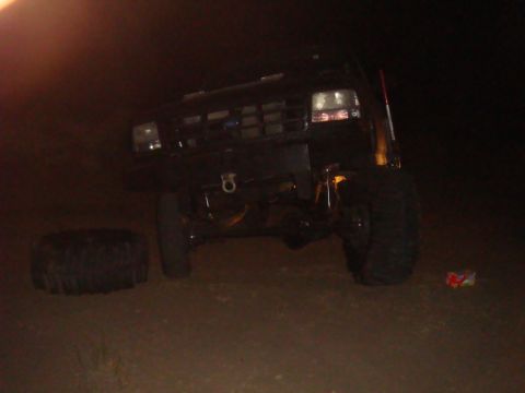 1992 Ford Bronco - A black 1992 Ford Bronco is parked with a flat tire and a spare tire visible on the ground.