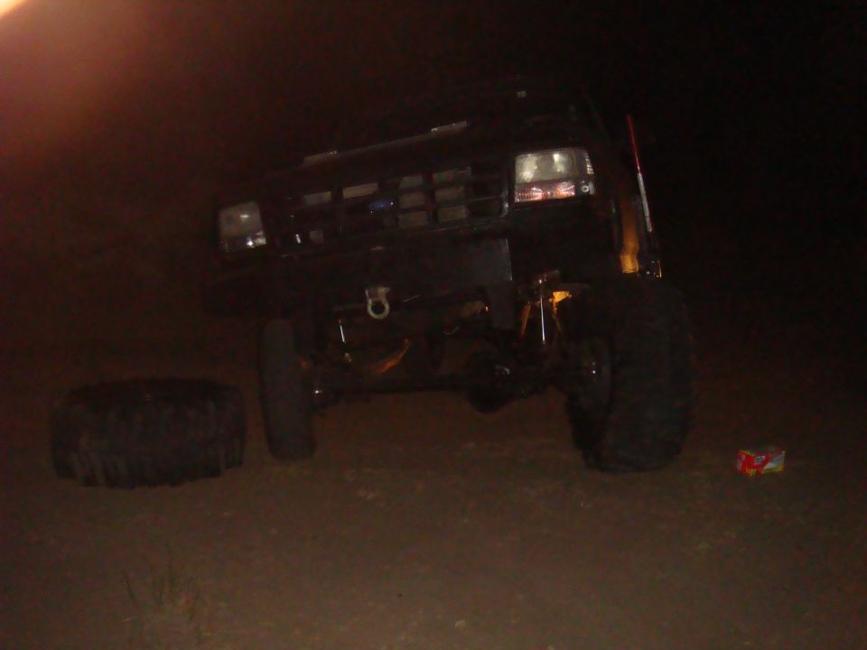 Black 1992 Ford Bronco with a flat tire and a spare tire on the ground