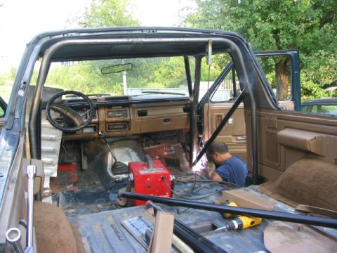 1986 Ford Bronco - A man welds a roll cage inside the interior of a 1986 Ford Bronco.