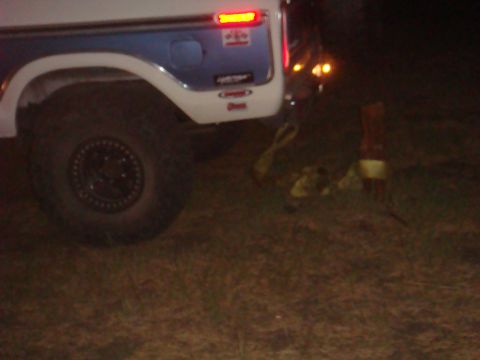1992 Ford Bronco - The rear of a vintage Ford Bronco is visible, with a spare tire and some straps lying on the ground.