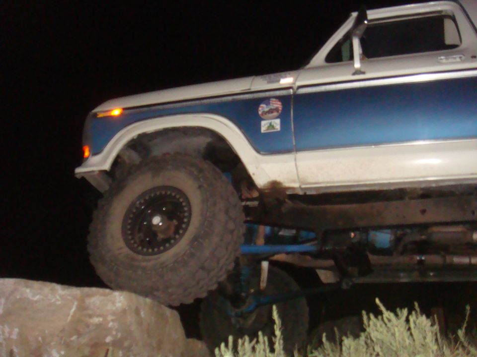 White and blue Ford Bronco with off-road tires on rocks