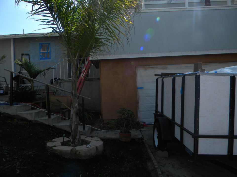 Trailer parked next to a garage with a palm tree in the foreground