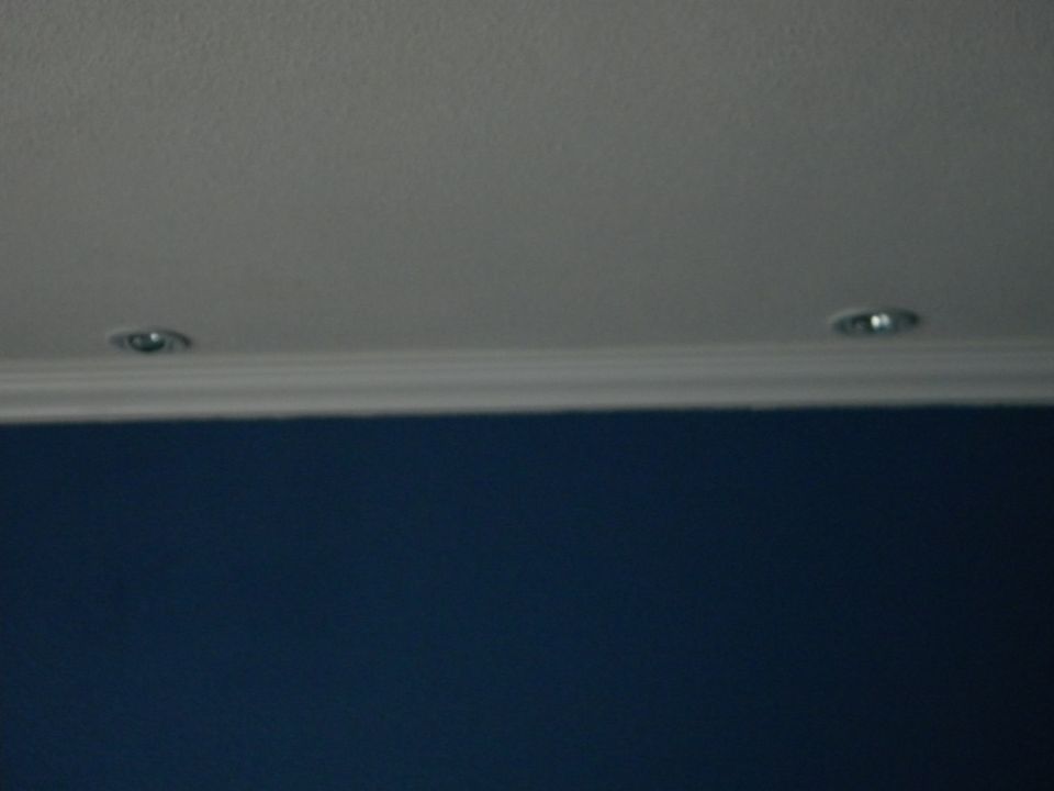 Two recessed ceiling lights above a blue wall and white molding