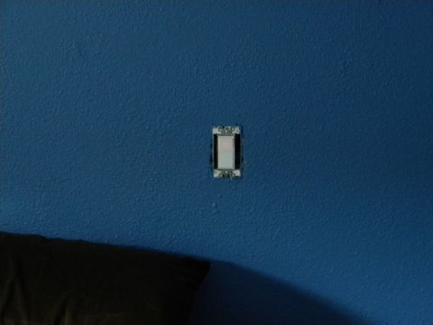 1992 Ford Bronco - A light switch is mounted on a textured blue wall, with a dark object in the lower left corner.