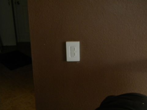 1992 Ford Bronco - A white light switch is mounted on a textured brown wall.