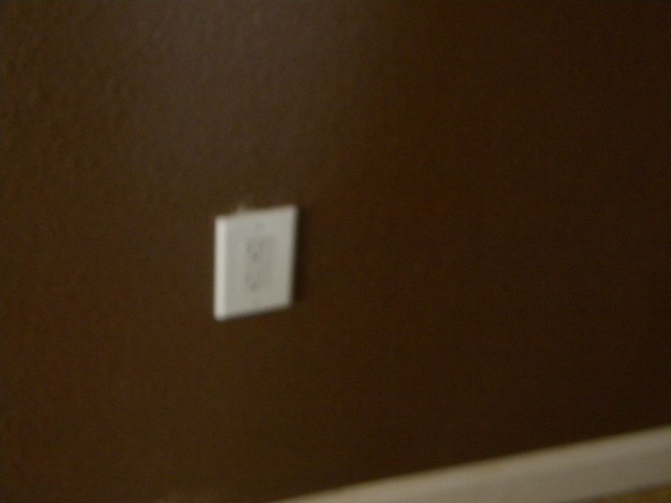 White electrical outlet on brown wall, with Supermotors.net watermark