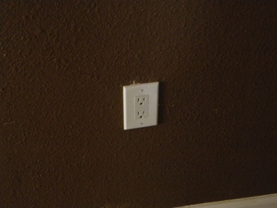Electrical outlet on a textured brown wall