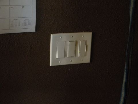 1992 Ford Bronco - A wall-mounted light switch plate with three switches is visible next to a calendar on a textured wall.