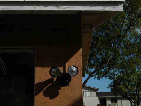 1992 Ford Bronco - An exterior floodlight is mounted on a textured wall, casting shadows under a bright sky.