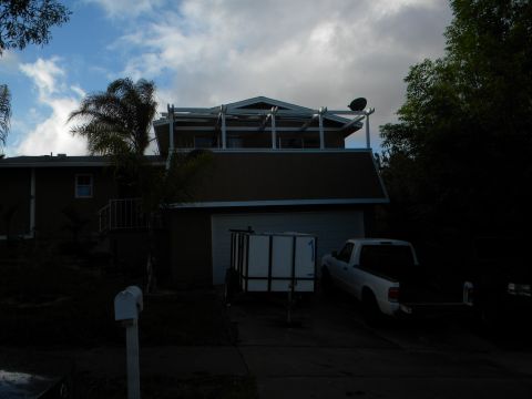 1992 Ford Bronco - A white pickup truck and a utility trailer are parked in a driveway in front of a house under a cloudy sky.