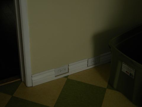 1992 Ford Bronco - A wall features multiple electrical outlets along the baseboard, next to a large green storage bin.