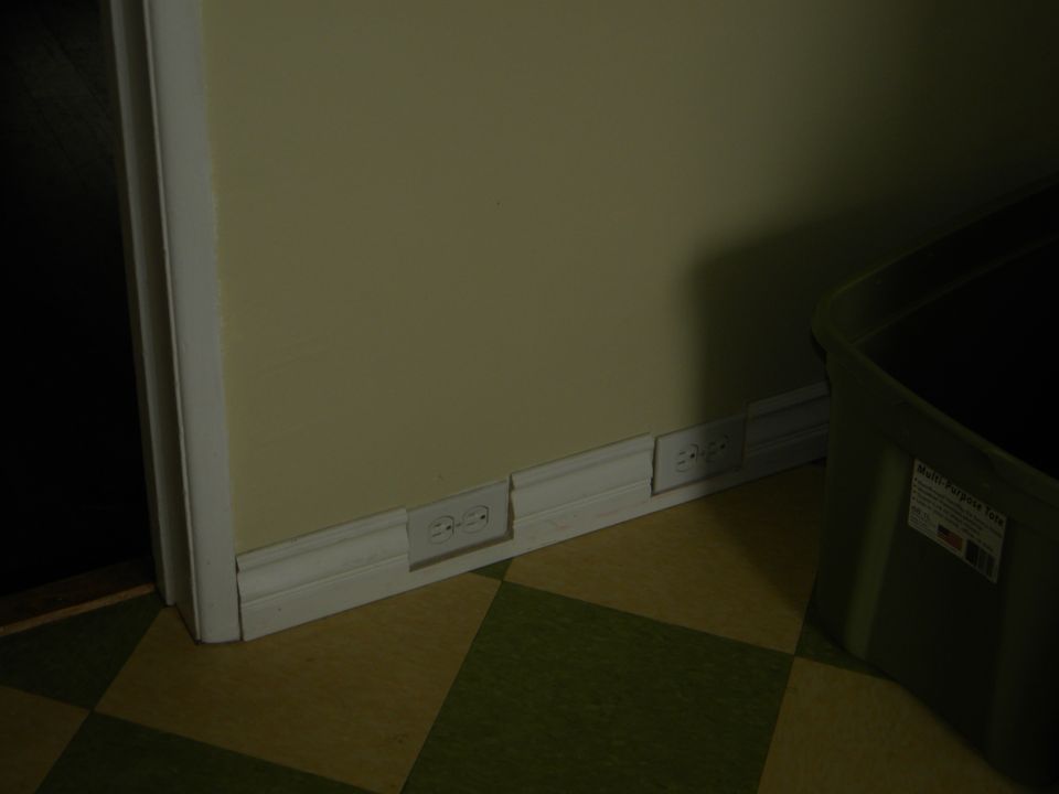 Wall with electrical outlets and a green storage bin