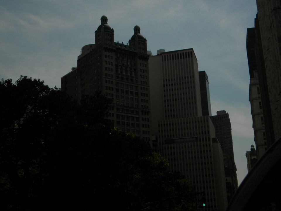 Cityscape with tall buildings and trees under a cloudy sky. Supermotors logo visible