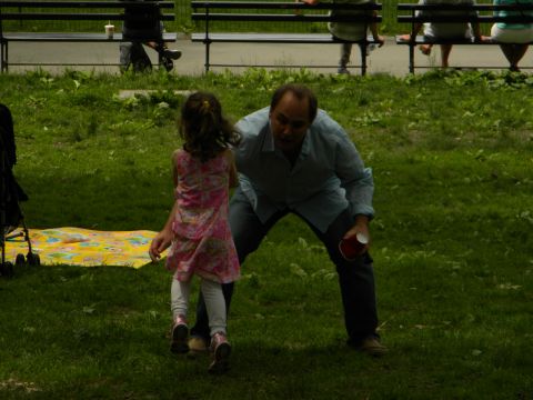 1992 Ford Bronco - A man and a child interact in a park setting, with benches and a picnic blanket visible in the background.
