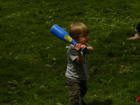 1992 Ford Bronco - A young boy grips a blue toy bat, ready to play in a sunlit, grassy field.