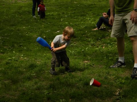 1992 Ford Bronco - Young child attempts to hit a red cup with a blue plastic baseball bat on a grassy field.
