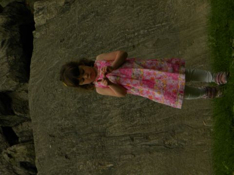 1992 Ford Bronco - A young girl in a pink floral dress stands near a large rock formation with grass in the background.