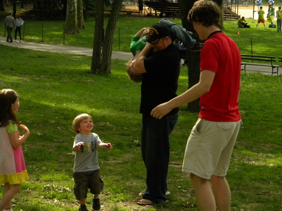 People interacting in a park with trees and benches, a watermark reads SUPERMOTORS
